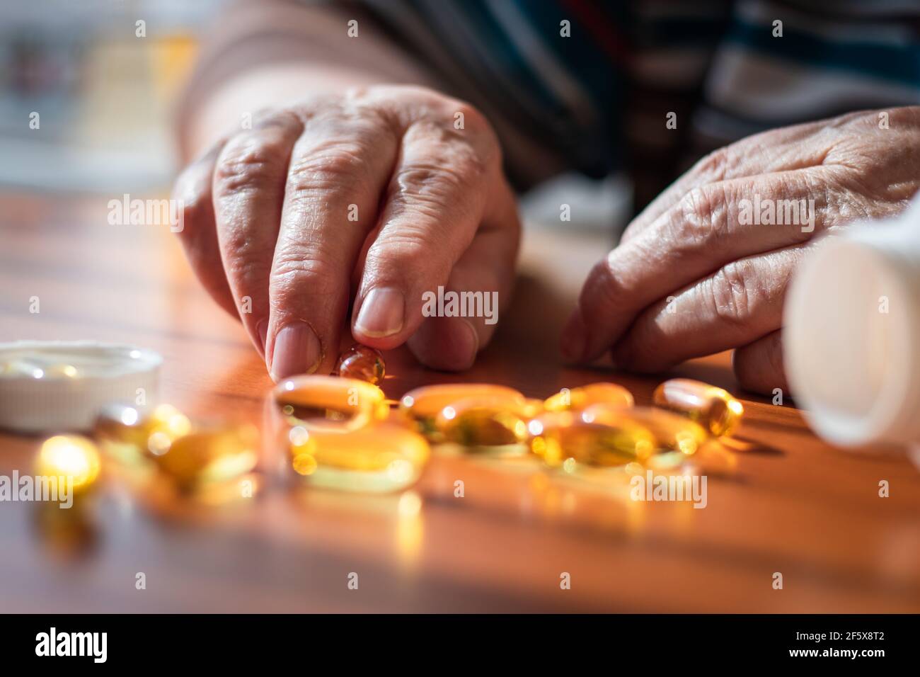 Mains de femmes âgées et capsule omega 3 sur la table. Supplément nutritionnel à l'huile de poisson. La vieille femme prend des pilules de vitamine D pour une bonne santé. Concept médical Banque D'Images