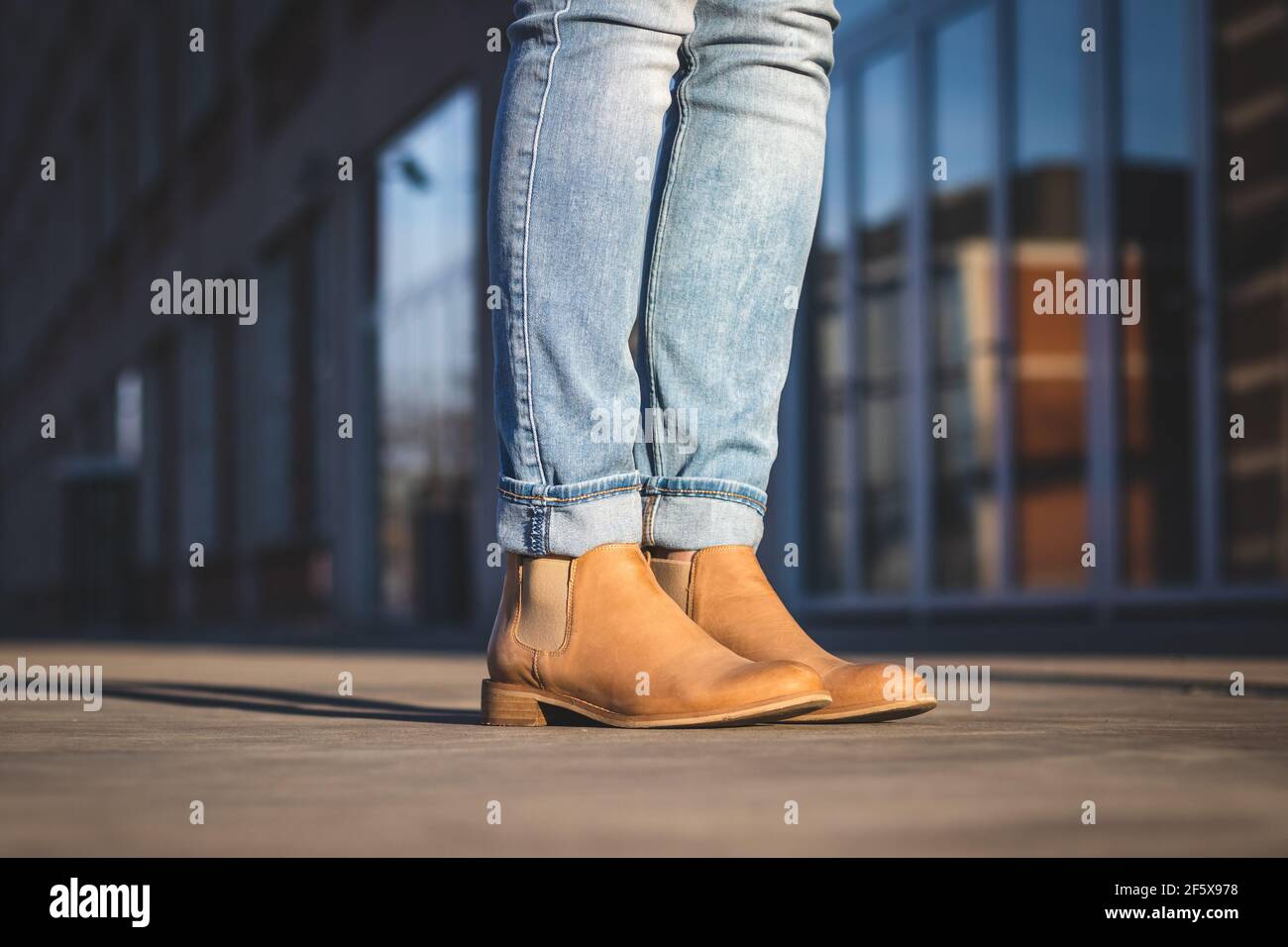 Les jambes des femmes portent un Jean et une botte en cuir en ville.  Architecture moderne avec réflexion sur le verre comme arrière-plan. Femme  debout sur la place Photo Stock - Alamy