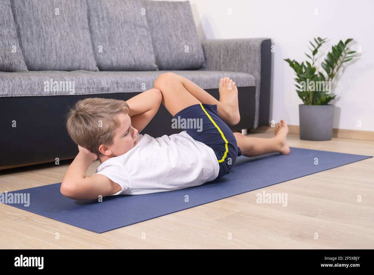 Un garçon blond entre pour le sport sur un tapis de yoga. Activité physique  de l'enfant à la maison. Sport sain style de vie loisirs actifs Photo Stock  - Alamy