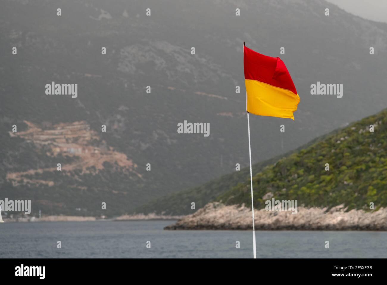 Un drapeau rouge et jaune qui saute la vie au bord de la mer. Banque D'Images