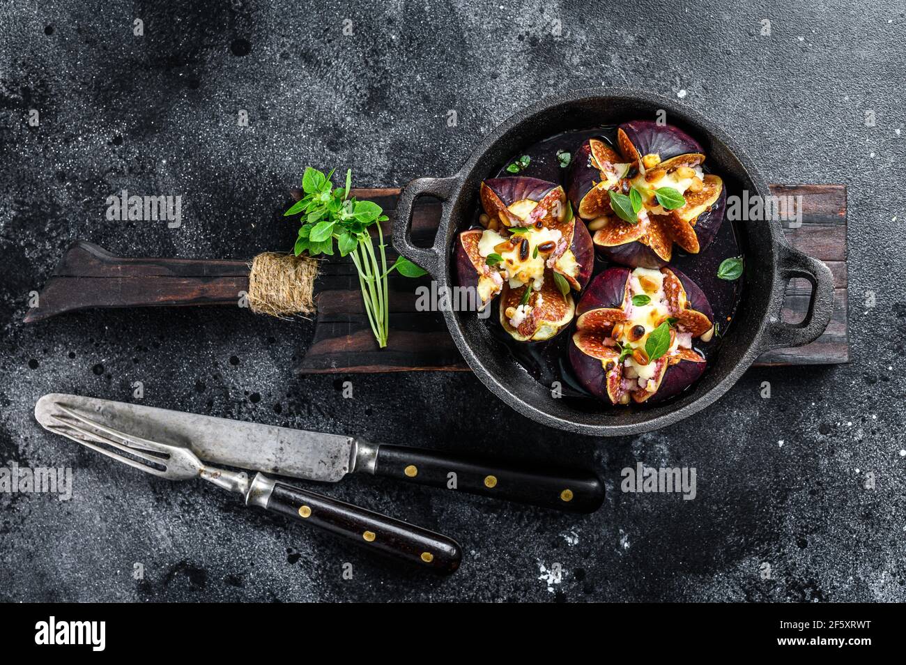 Figues au four avec fromage à la crème, miel et noix. Arrière-plan noir. Vue de dessus Banque D'Images
