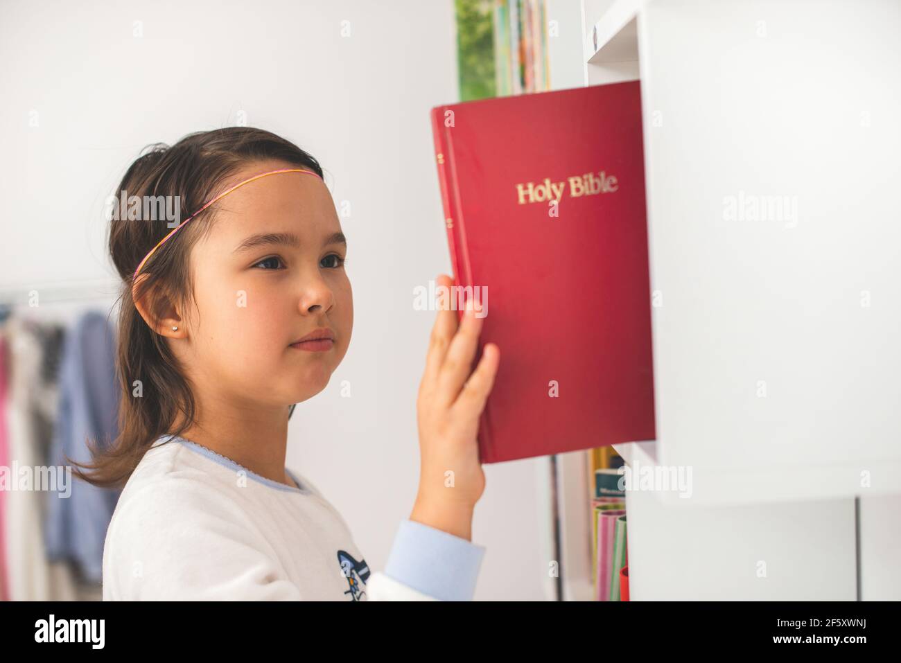 Peu de prendre la bible de sa bibliothèque Banque D'Images