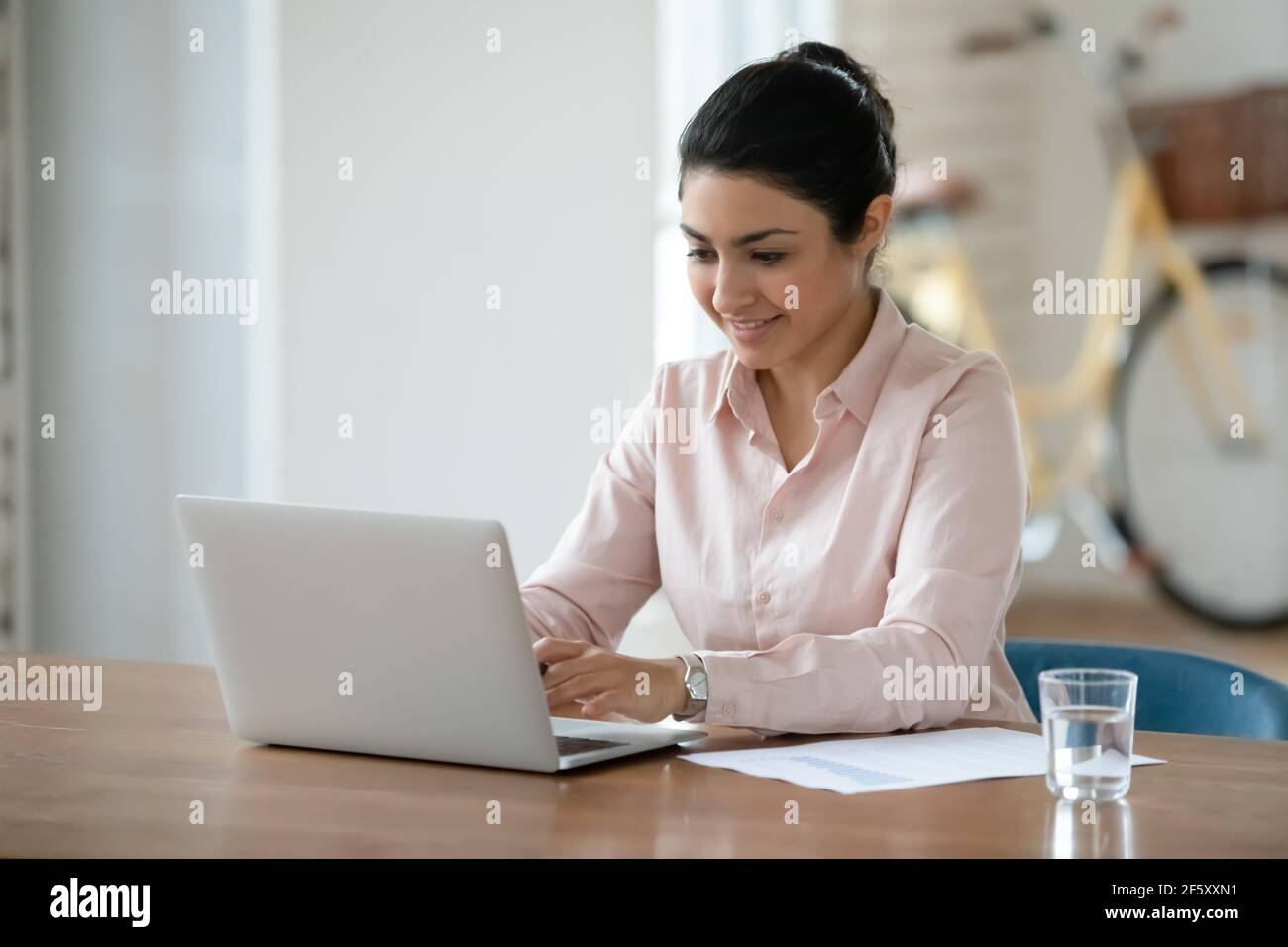 Une femme indienne souriante travaille sur un ordinateur portable Banque D'Images