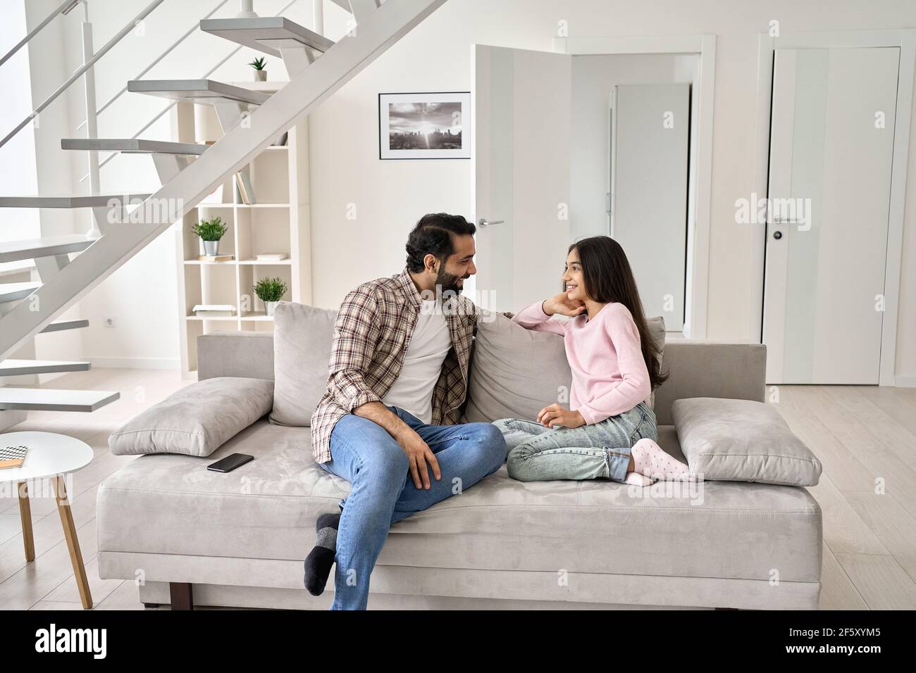 Père indien heureux et fille adolescente appréciant parler à la maison. Banque D'Images