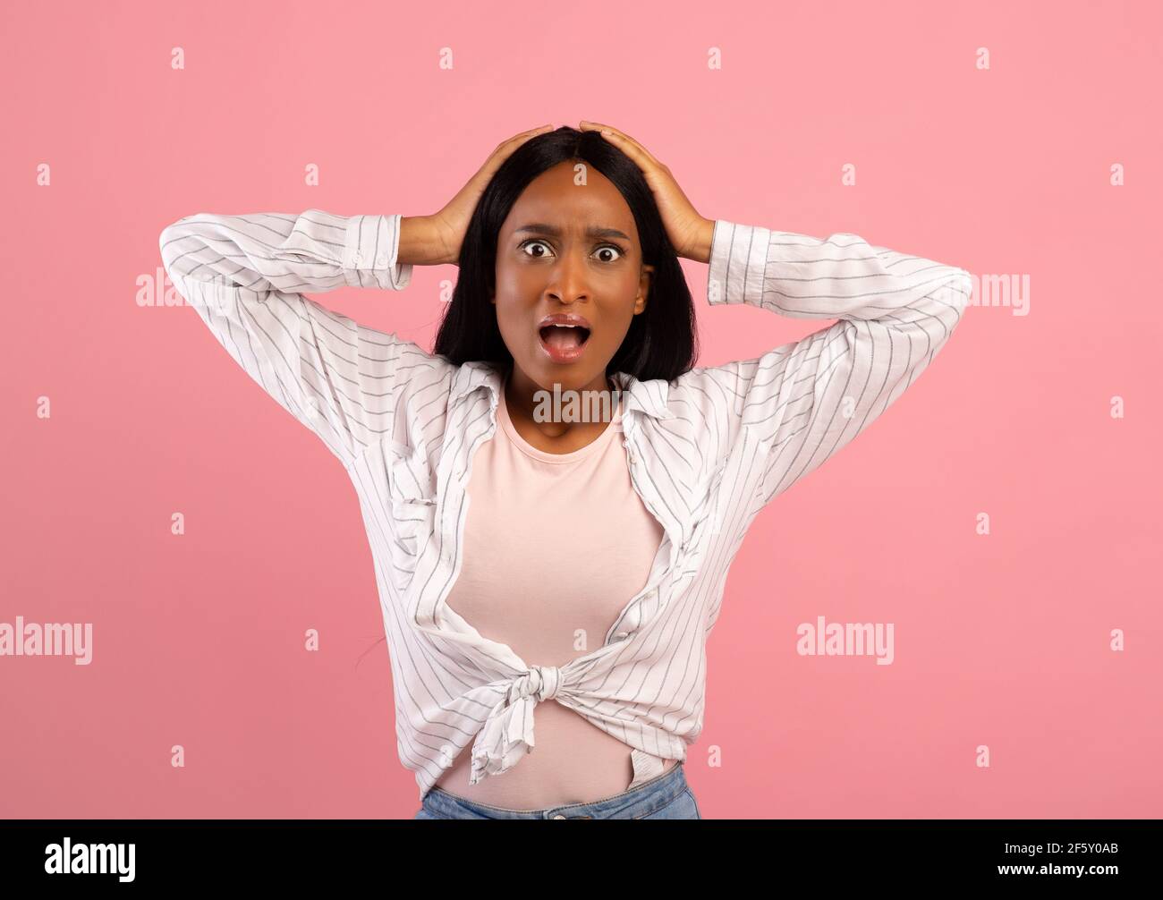 Des nouvelles incroyables. Femme noire émotive tenant sa tête en choc sur fond rose studio Banque D'Images
