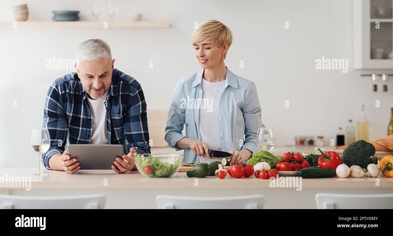Cuisinez des plats faits maison pendant la pandémie de Covid-19, l'application de recettes et le surf sur Internet Banque D'Images