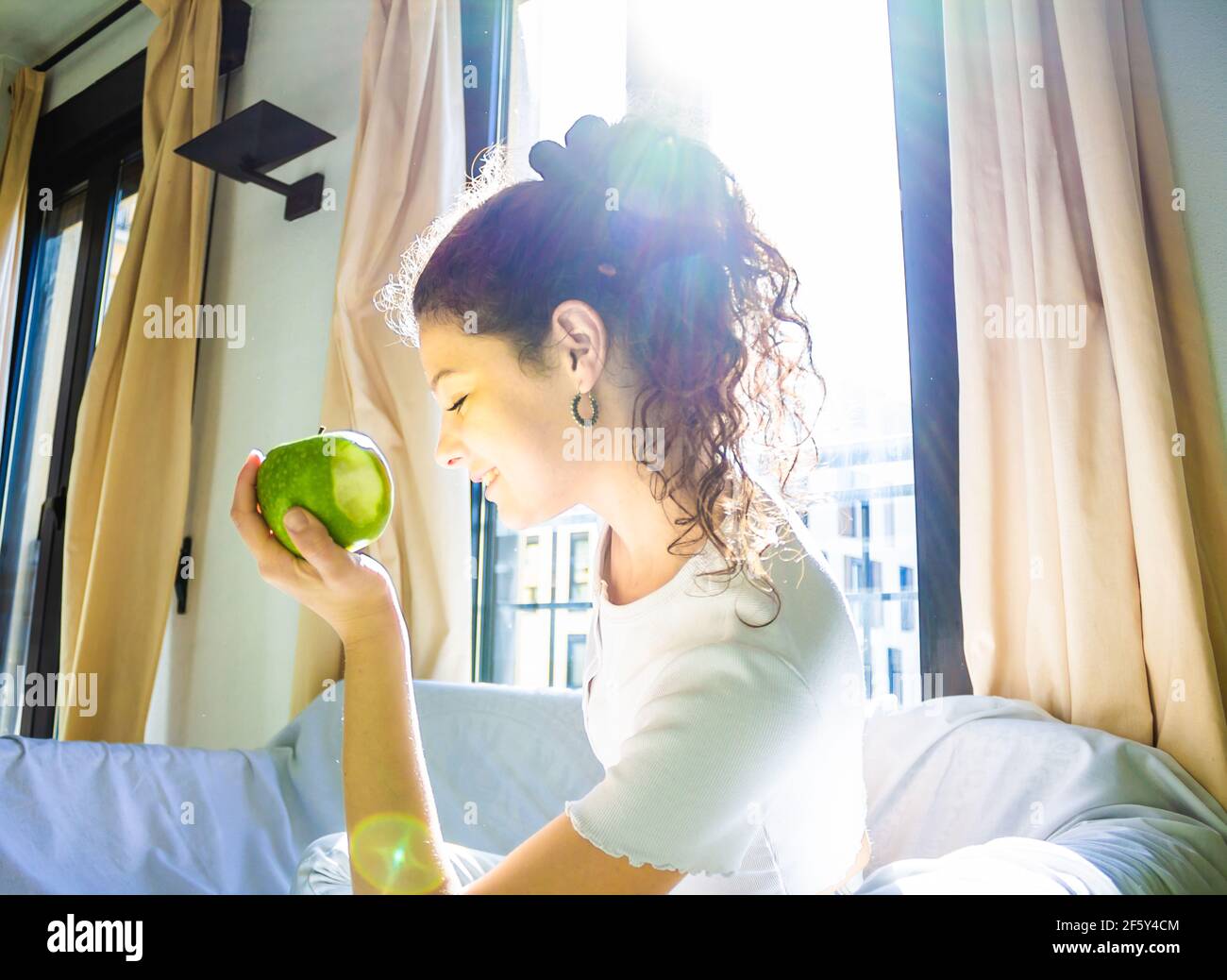 jeune femme mangeant une pomme verte sur le canapé à accueil Banque D'Images