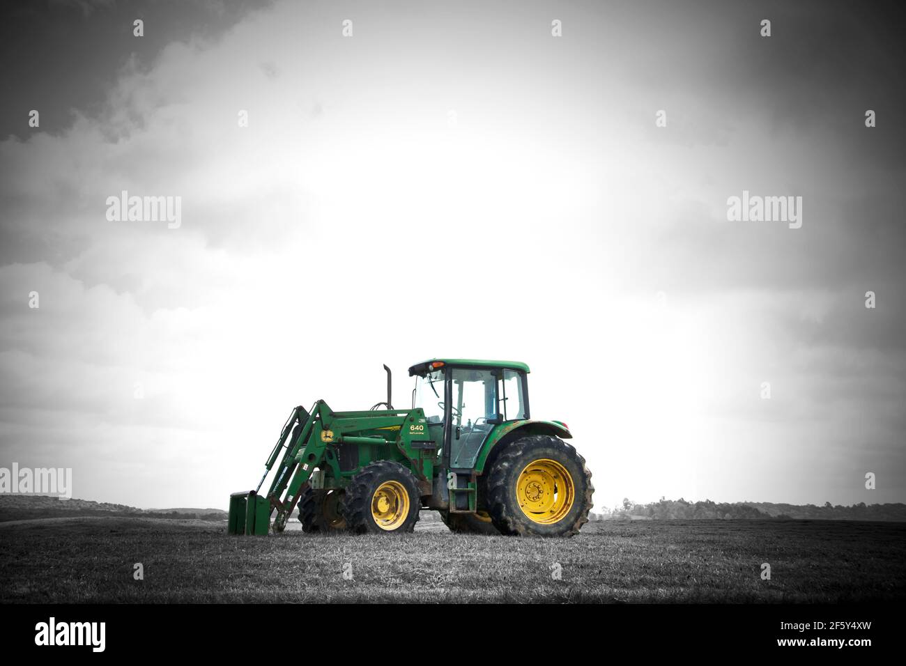 John Deere Green Tractor sur la ferme au coucher du soleil noir et blanc avec coloration sélective Banque D'Images