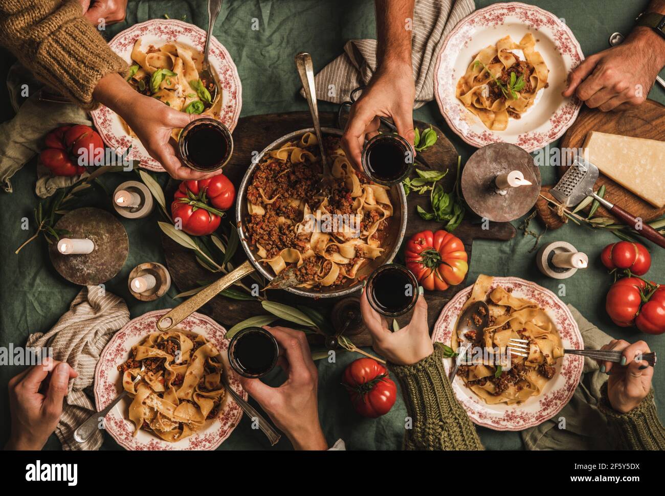 Les personnes qui mangent des pâtes bolognaises avec du vin à la table du dîner en famille Banque D'Images