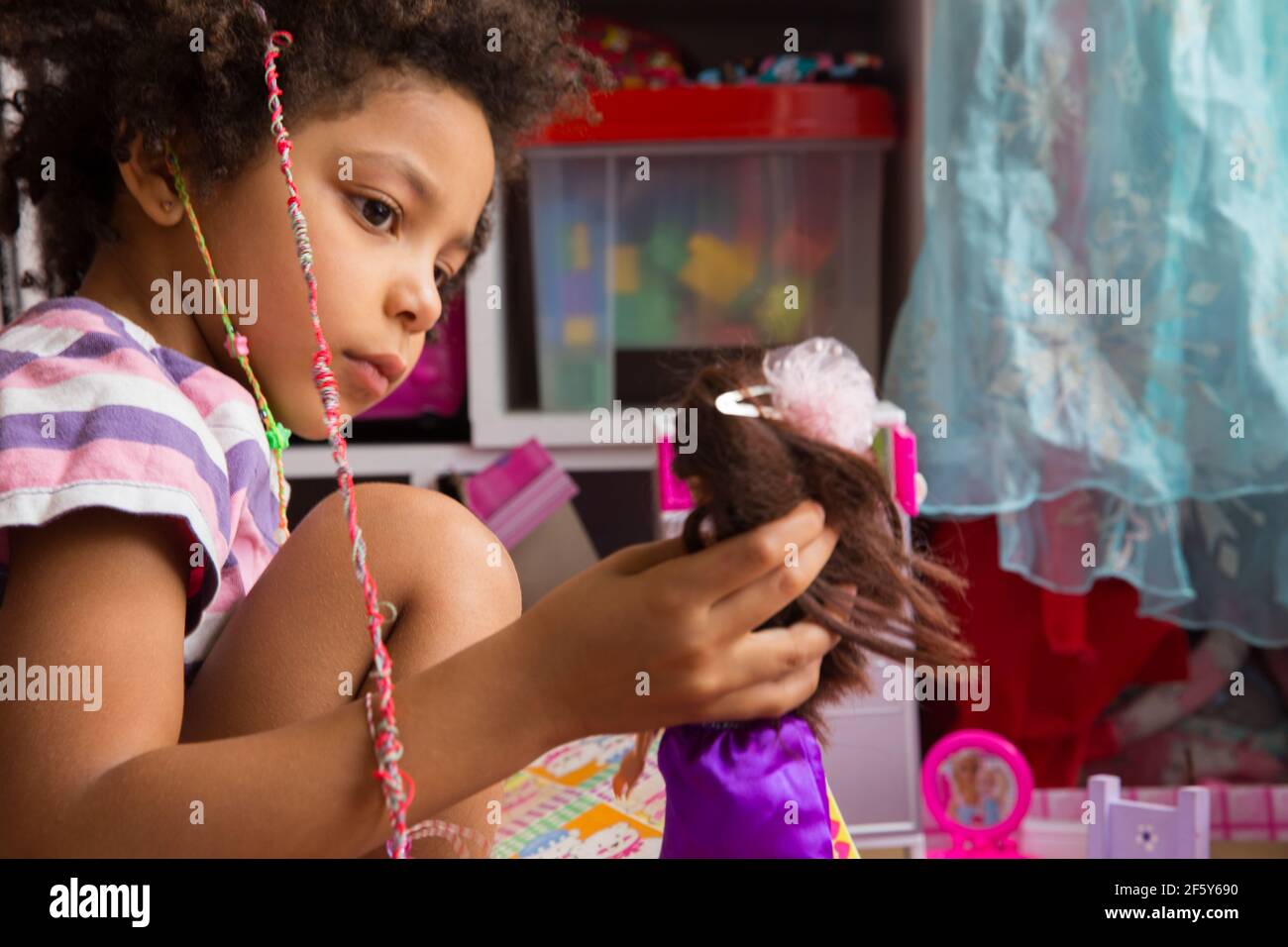 Race mixte petite fille jouant avec la poupée assis dans coloré salle de jeux Banque D'Images