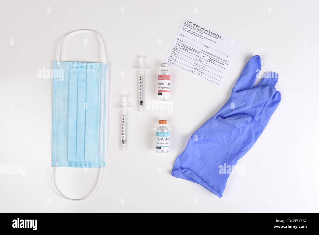 Équipement pour administrer une vaccination Covid19 avec une carte d'enregistrement. Poser à plat avec masque chirurgical, seringues, flacons de vaccins et gants. Banque D'Images