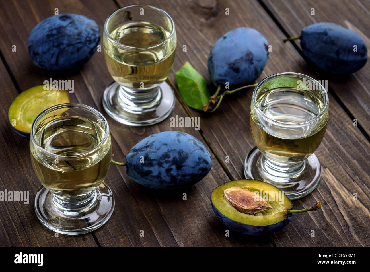 Brandy aux prunes ou schnaps dans des verres et prunes fraîches et savoureuses sur une table en bois. Mise au point sélective. Banque D'Images