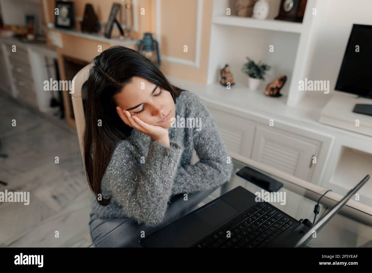 Une jeune femme stressée portant des lunettes et un chandail est assis dans le salon à la maison est fatigué d'étudier en cours en ligne Banque D'Images