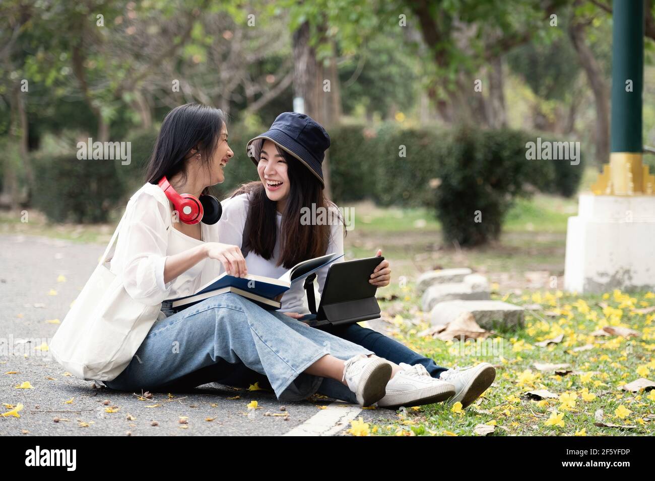 Deux étudiants heureux assis et parlant l'un l'autre dans un campus au parc. Banque D'Images