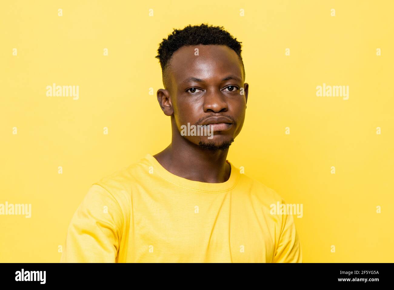 Le jeune homme africain est face sur fond isolé jaune stuido Banque D'Images