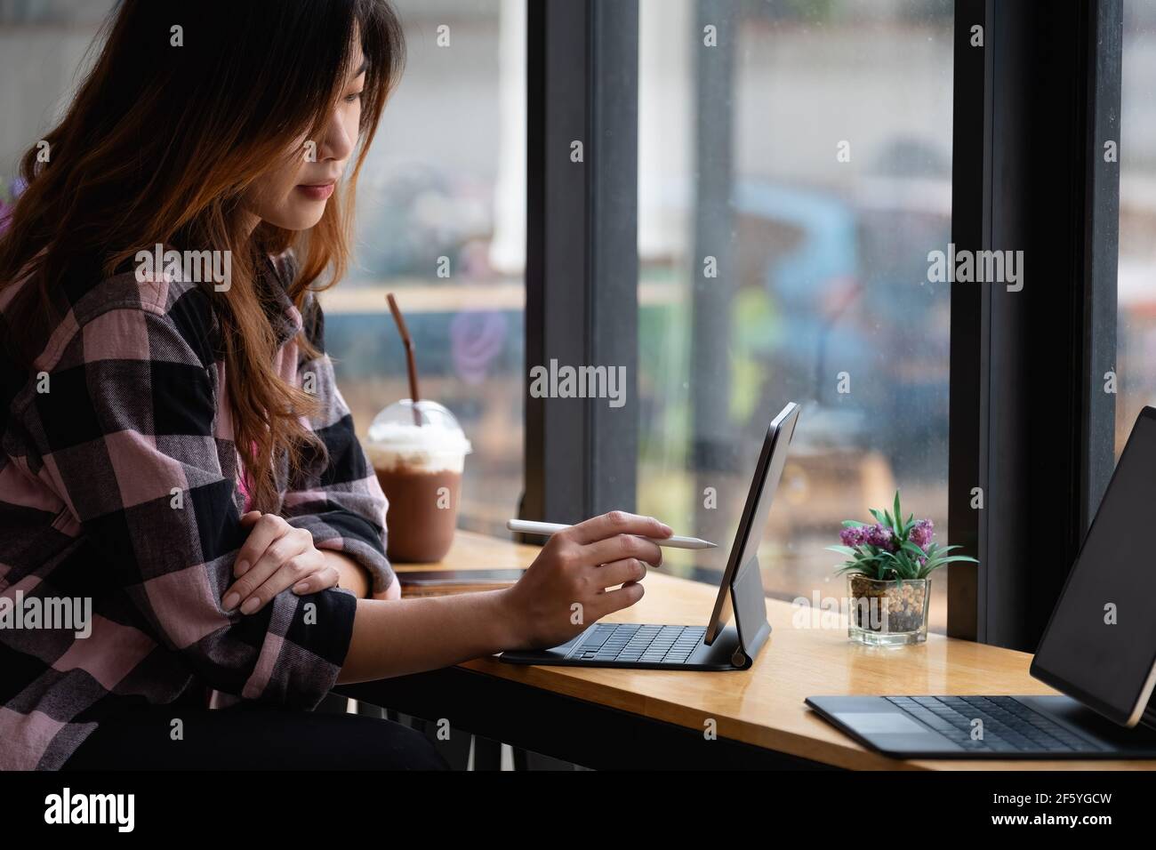 Jeune créateur tenant le stylet dessin à l'écran de tablette numérique au café Banque D'Images