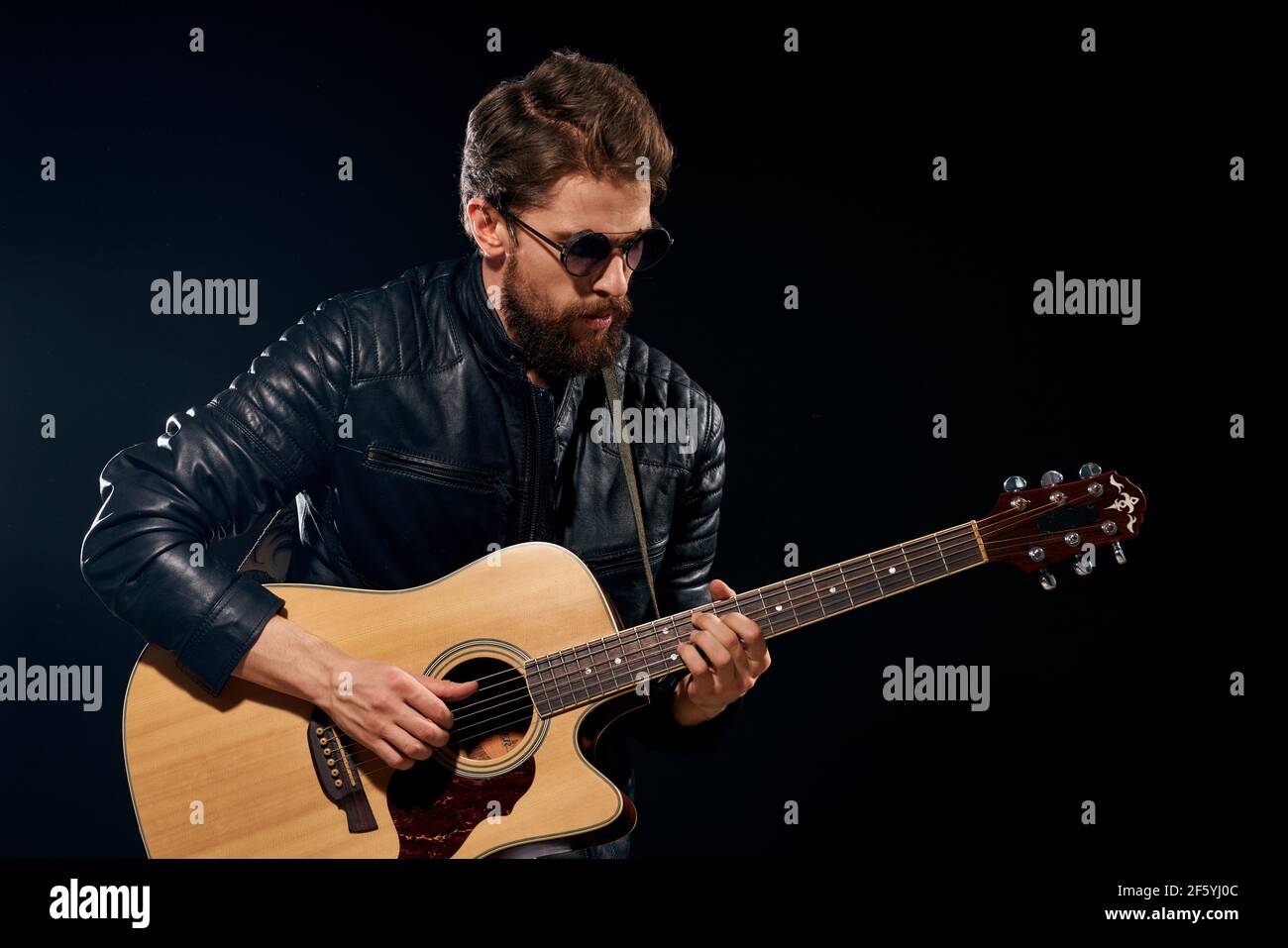 homme avec une guitare dans ses mains blouson en cuir noir lunettes de  soleil musique émotions fond noir Photo Stock - Alamy