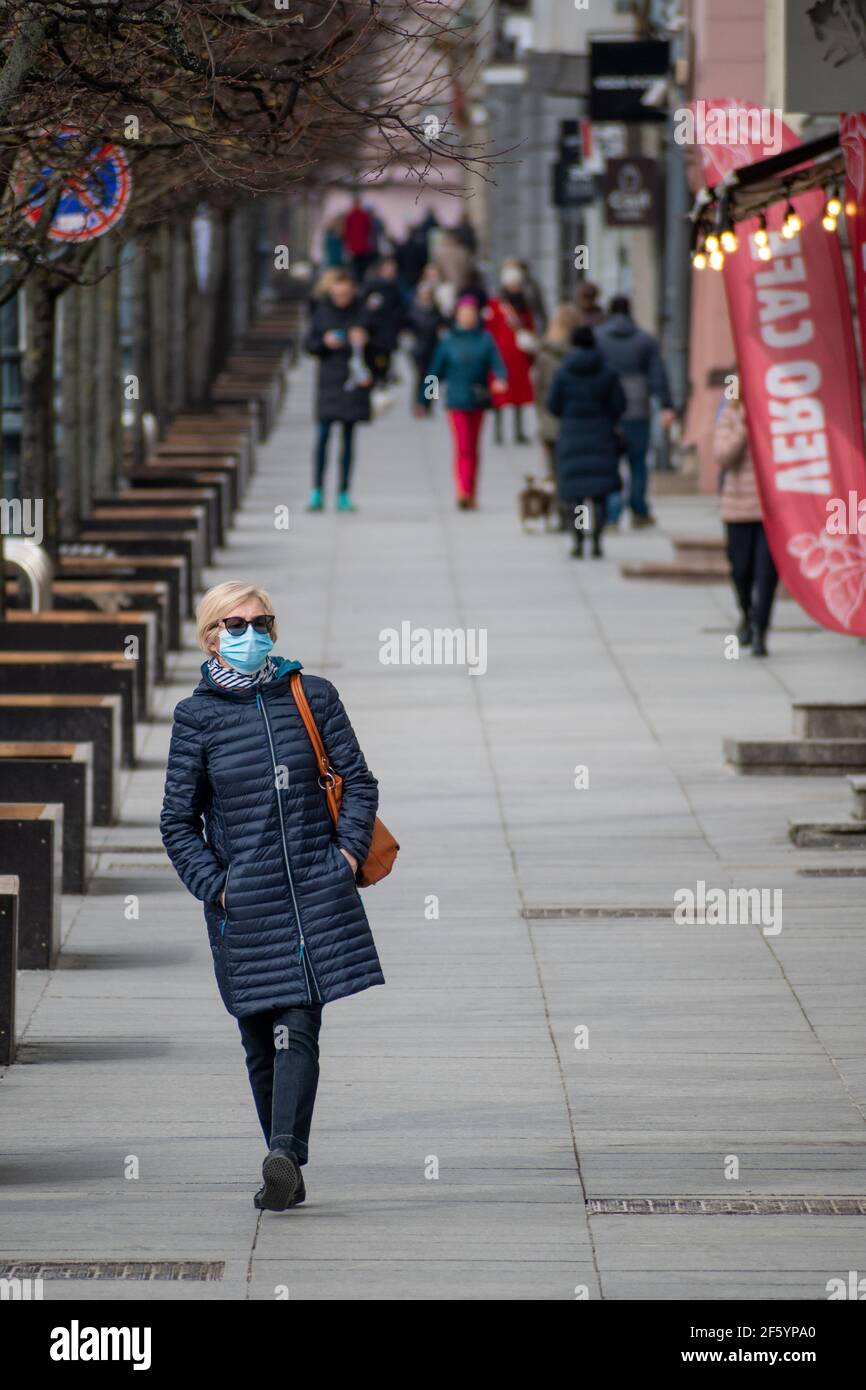 Femme ou femme portant un masque marchant dans le centre-ville pendant les restrictions de Covid ou de coronavirus, vertical Banque D'Images