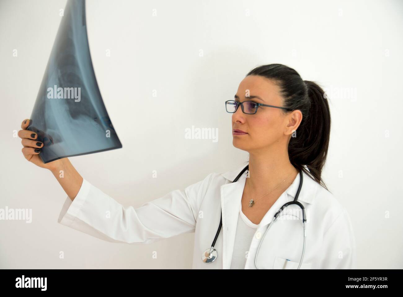 une jeune femme médecin avec des lunettes examine la radiographie sur sa main. Face de mise au point sélective Banque D'Images