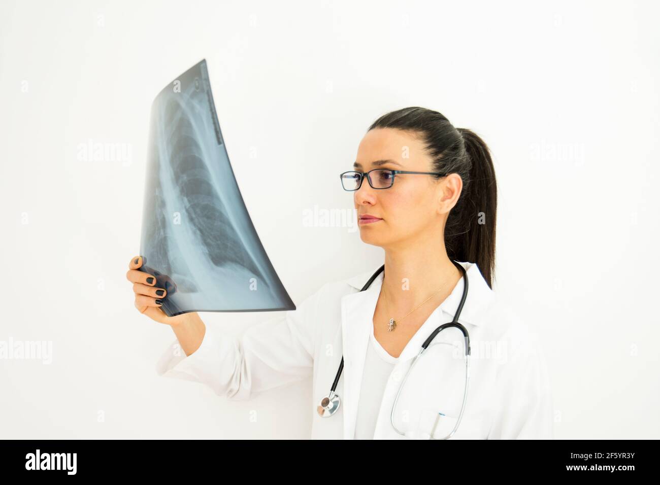 une jeune femme médecin avec des lunettes examine la radiographie sur sa main. Face de mise au point sélective Banque D'Images