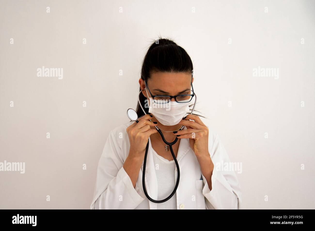 Portrait d'un médecin dans un angle différent et lumières devant un mur blanc. Face de mise au point sélective. Banque D'Images