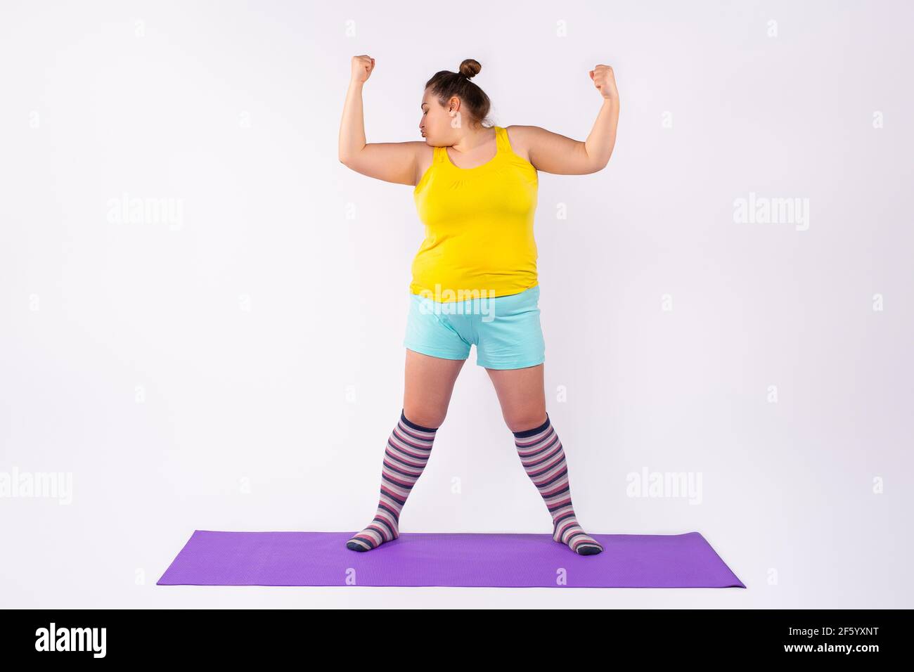 Fitness à domicile, entraînement en ligne avec un ordinateur portable couleur gris ultime. Embonpoint, plump femme regardant tutoriel vidéo faire stretching exerciseon tapis de fitness Banque D'Images