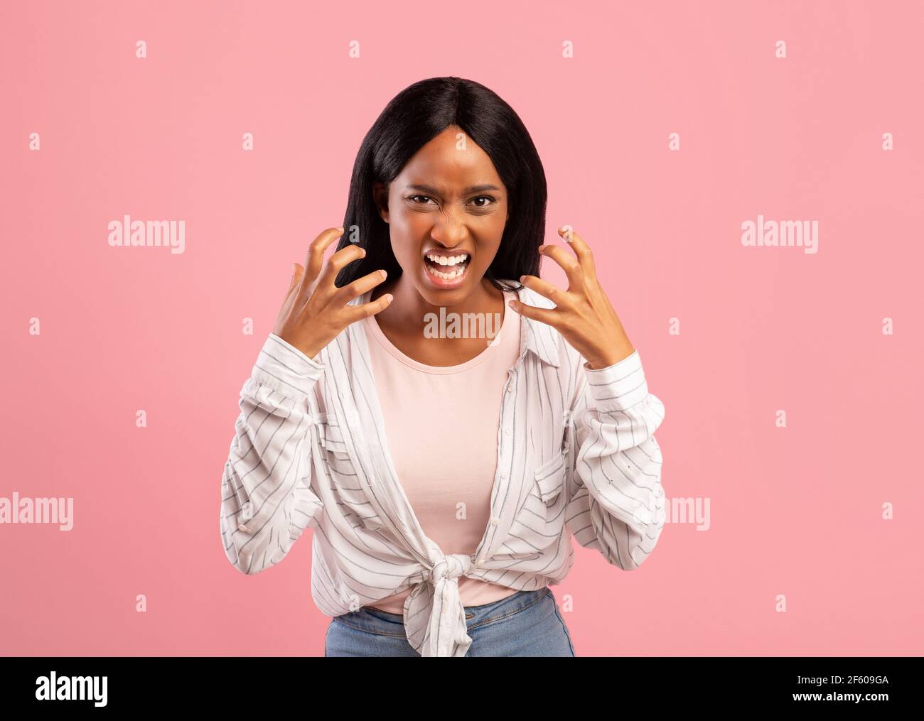 Une femme noire en colère criait à haute voix, fatiguée de ses problèmes, exprimant des émotions négatives sur fond rose studio Banque D'Images