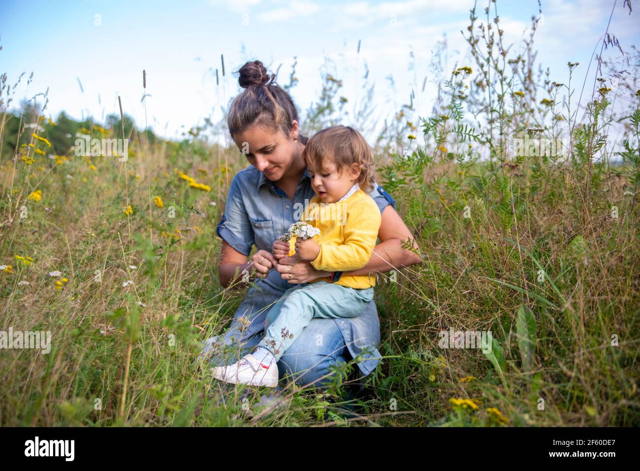 une jeune mère et une petite fille collectent un bouquet de fleurs sauvages fleurs yarrow-up Banque D'Images