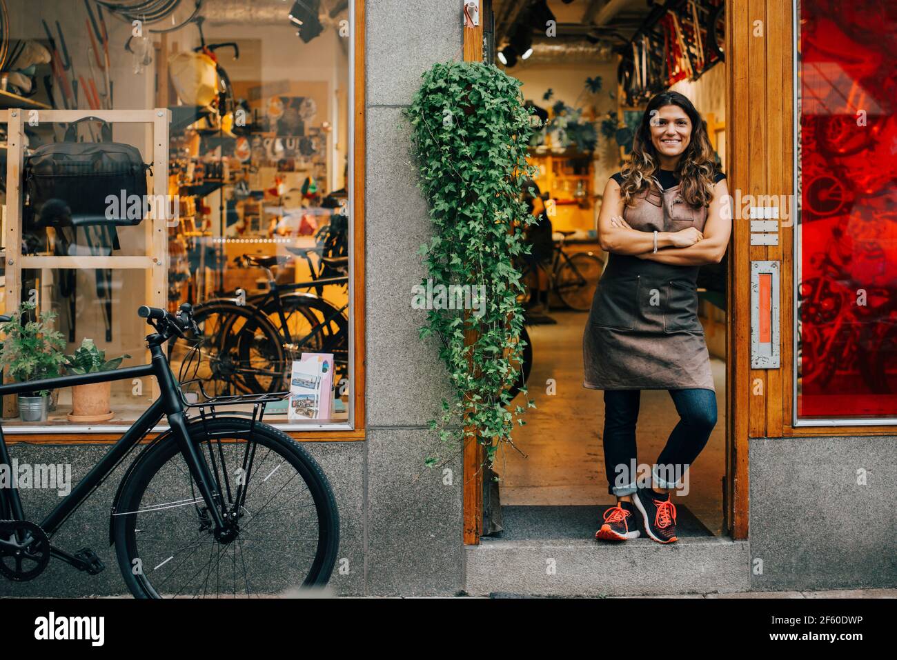 Portrait de l'expertise féminine avec les bras croisés debout sur la porte du magasin de vélos Banque D'Images