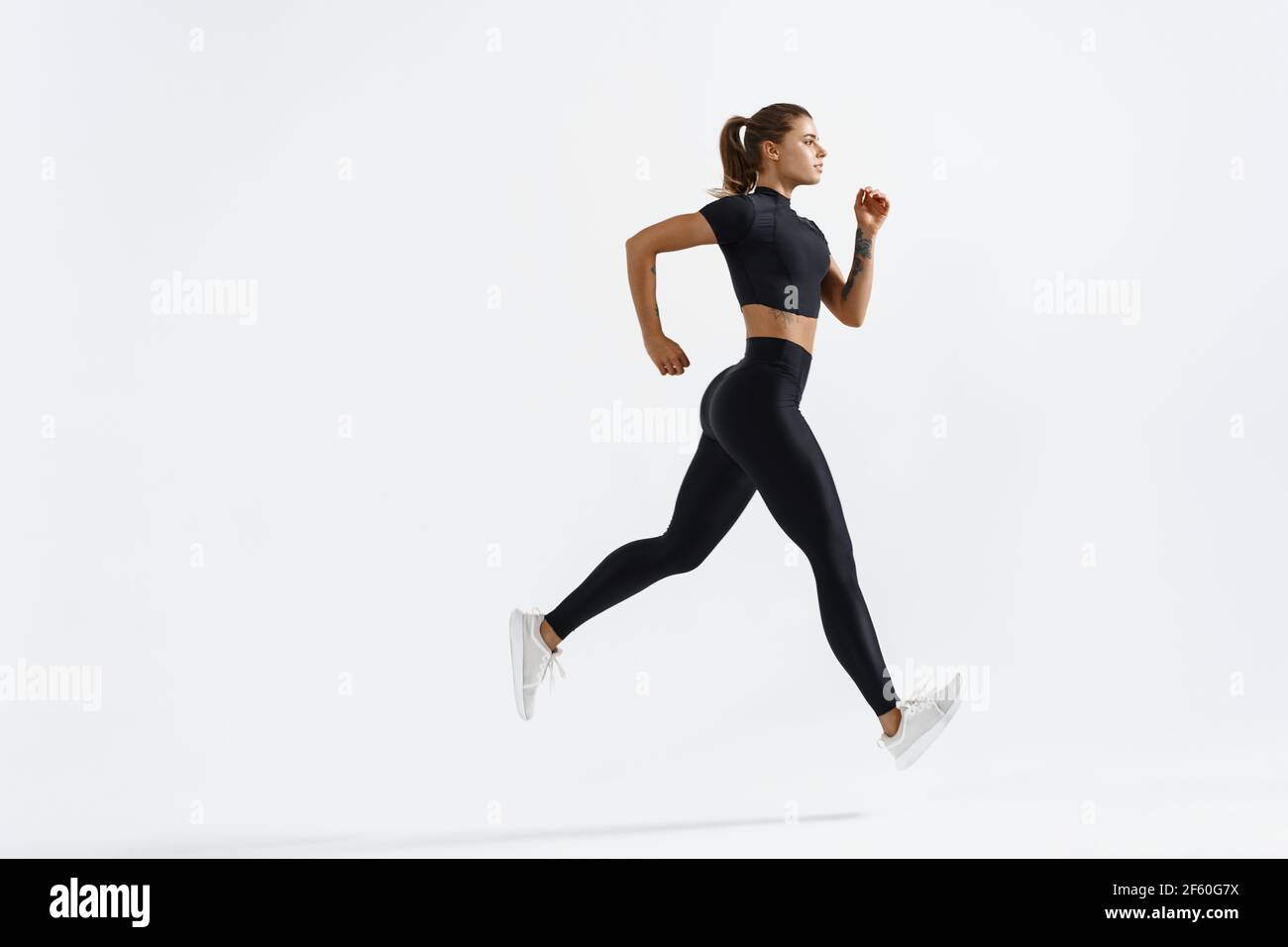 Sport fitness coureur fille, silhouette de femme jogging sur fond blanc  dans des vêtements de sport noirs, portant des vêtements de sport actif de  sport pendant l'entraînement, la course à pied Photo