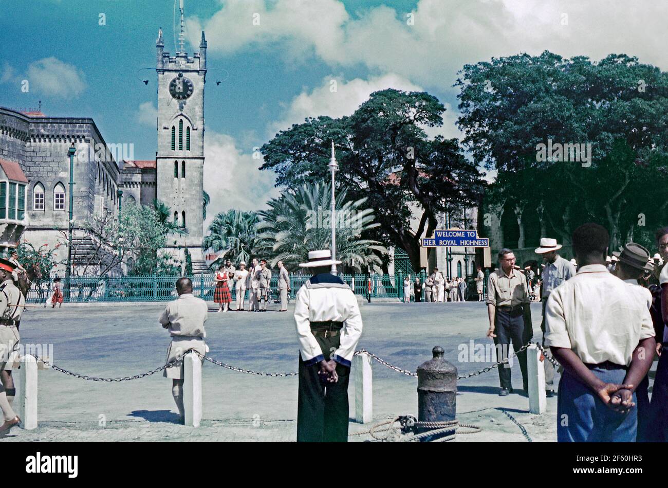 Scènes de foule à Bridgetown, Barbade, 1955, lors de la tournée de la princesse Margaret dans les Caraïbes. Ici, un panneau de bienvenue est affiché à l'extérieur des édifices du Parlement néo-gothique sur la place du Parlement. En janvier 1955, la Princesse a fait le premier de nombreux voyages dans les Caraïbes, sa visite à bord de Britannia aux colonies britanniques était populaire dans les Antilles. La princesse Margaret (1930 – 2002) était la fille plus jeune du roi George VI et de la reine Elizabeth, et la sœur de la reine Elizabeth II Cette image provient d'une ancienne transparence couleur 35 mm amateur, une photographie vintage des années 1950. Banque D'Images
