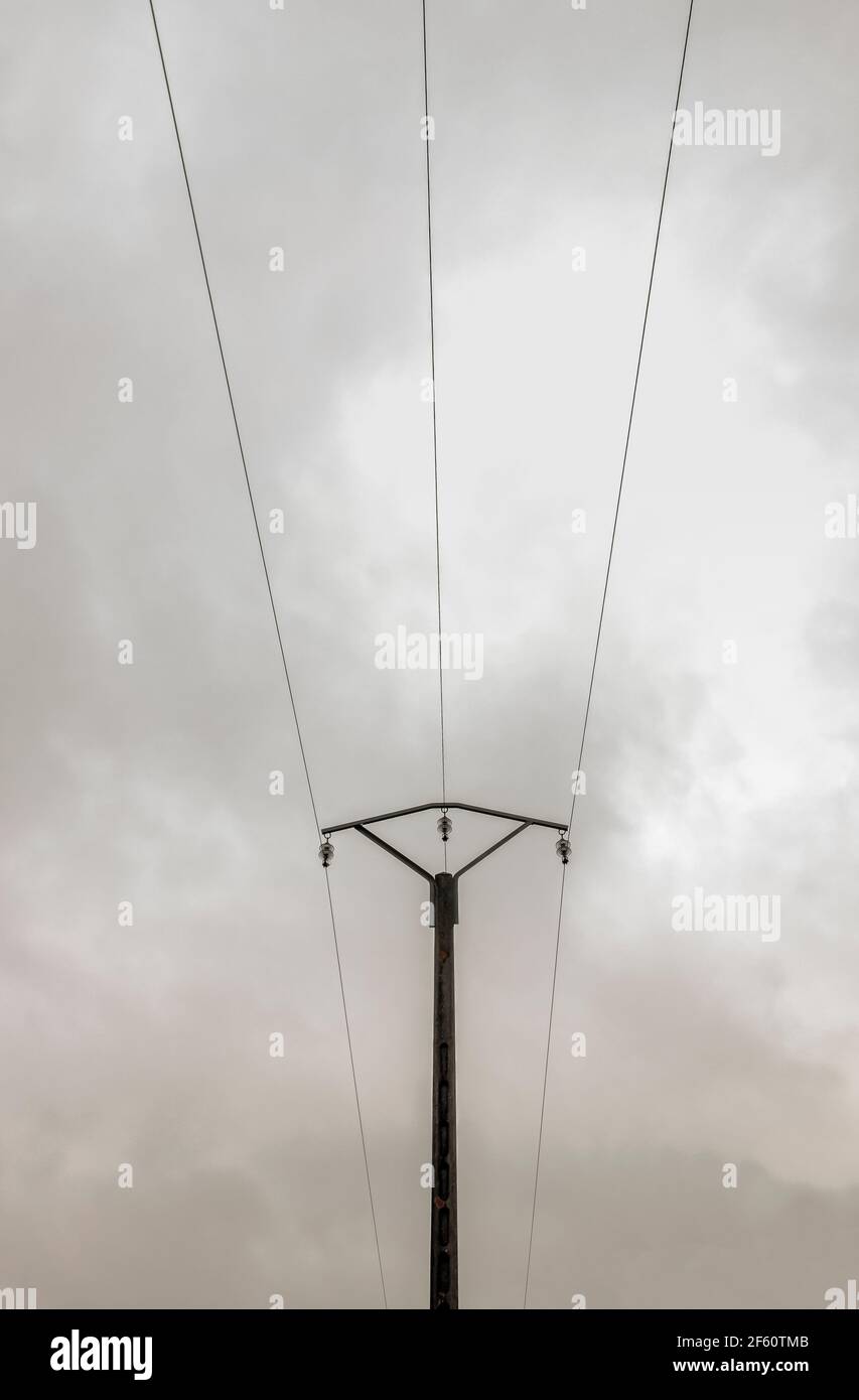 Poteau électrique en béton à trois fils, composition symétrique, ciel nuageux. France Banque D'Images
