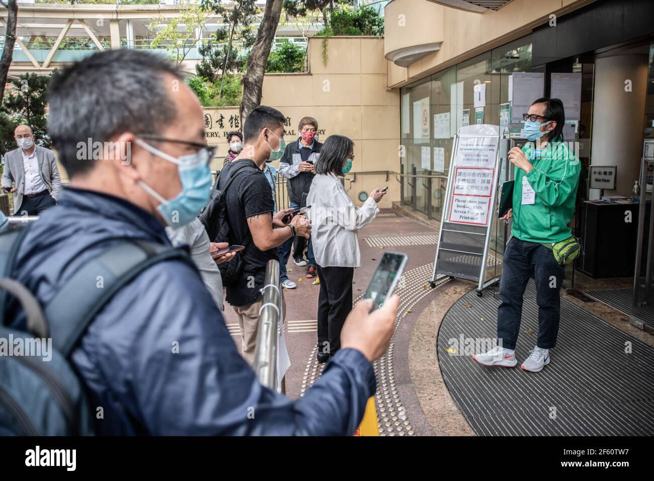 Hong Kong, Chine. 18 mars 2021. Un membre du personnel du Centre communautaire de vaccination s'entretient avec des participants à l'extérieur de la Bibliothèque centrale de Hong Kong. Les citoyens de Hong Kong assistent au Centre communautaire de vaccination situé dans l'une des galeries de la Bibliothèque centrale de Hong Kong, dans le district de Tai Hang, le jeudi 18 mars. Crédit : SOPA Images Limited/Alamy Live News Banque D'Images