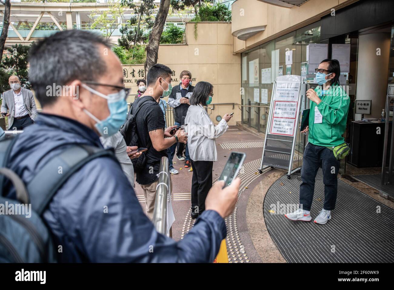 Hong Kong, Chine. 18 mars 2021. Un membre du personnel du Centre communautaire de vaccination s'entretient avec des participants à l'extérieur de la Bibliothèque centrale de Hong Kong. Les citoyens de Hong Kong assistent au Centre communautaire de vaccination situé dans l'une des galeries de la Bibliothèque centrale de Hong Kong, dans le district de Tai Hang, le jeudi 18 mars. Credit: Ivan Abreu/SOPA Images/ZUMA Wire/Alay Live News Banque D'Images