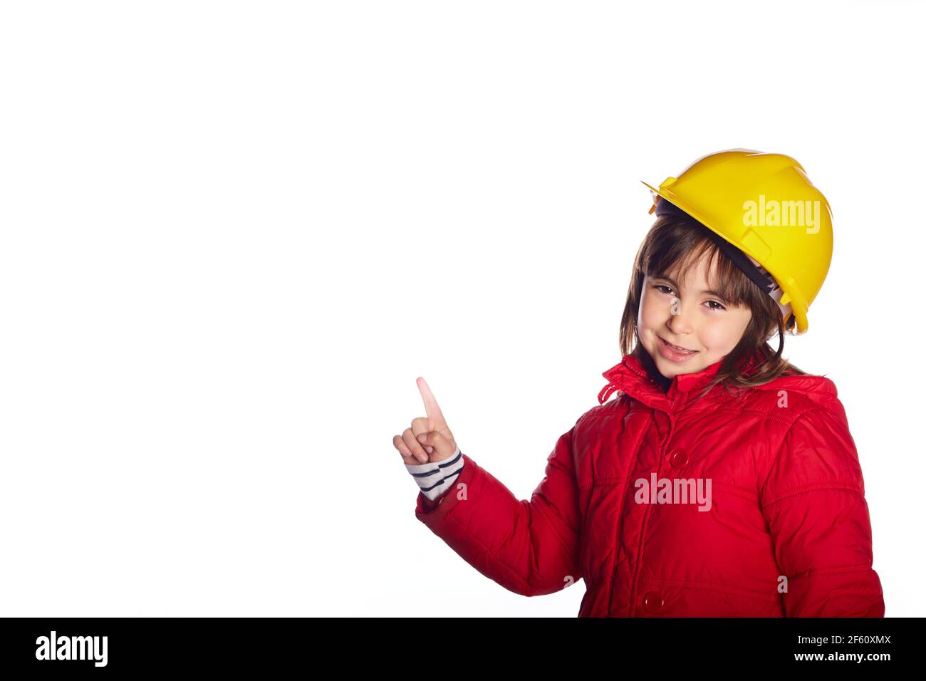 format paoramique fille de 4 ans souriant pointant du doigt vers un espace vide avec un casque de construction jaune regarder l'appareil photo avec l'espace de copie Banque D'Images