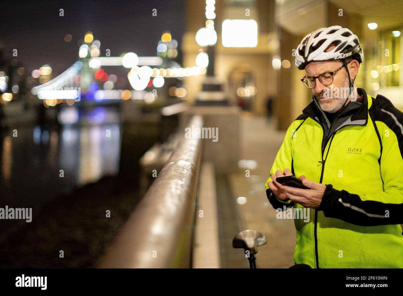 Cycliste utilisant le téléphone dans la ville la nuit, Londres, Royaume-Uni Banque D'Images