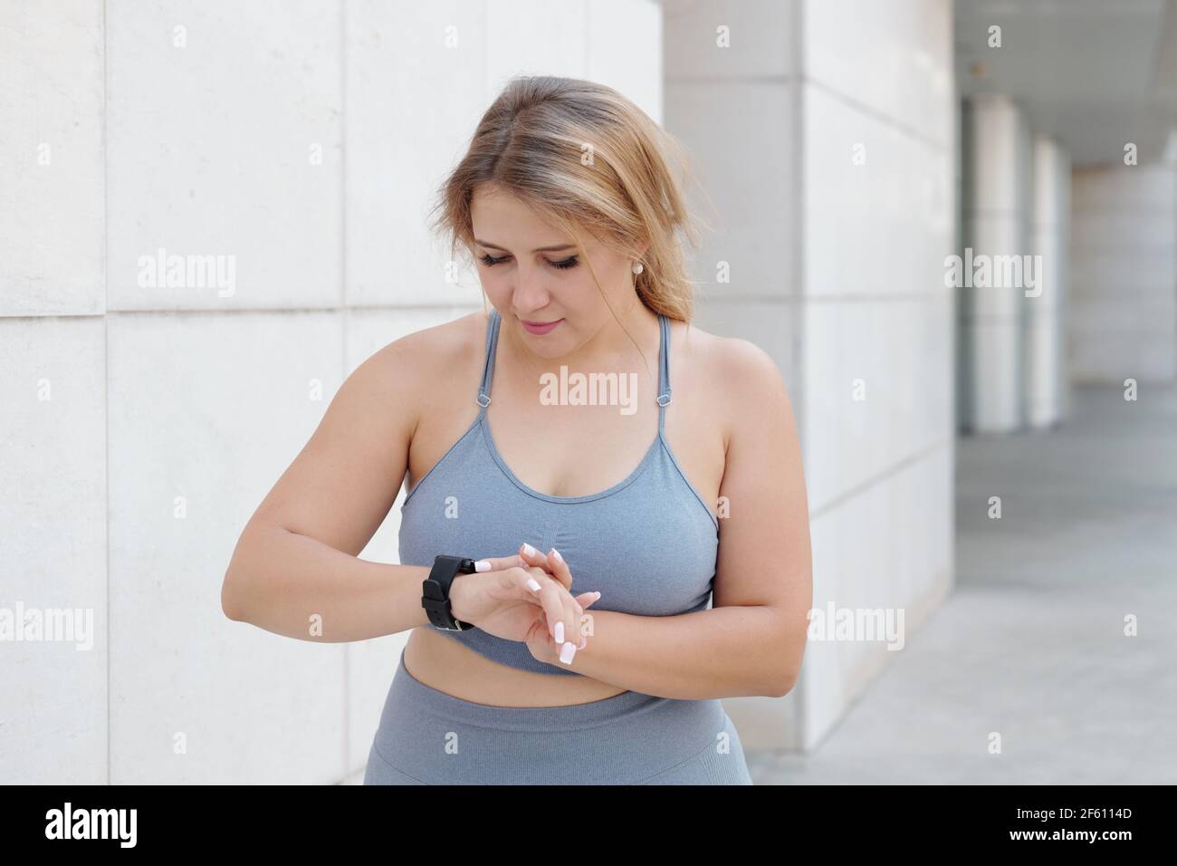 Femme de taille plus jolie qui vérifie son activité et s'ammount de calories brûlées via l'application sur le smartphone Banque D'Images