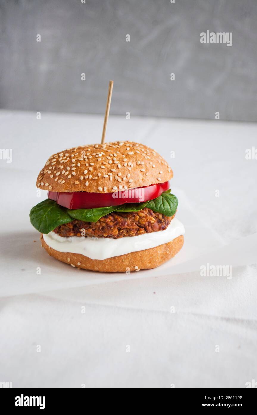 Hamburger végétalien à base de haricots rouges, de poivron rouge, d'épinards et de yaourt blanc. Délicieux hamburger végétarien frais sur une planche à découper. Banque D'Images