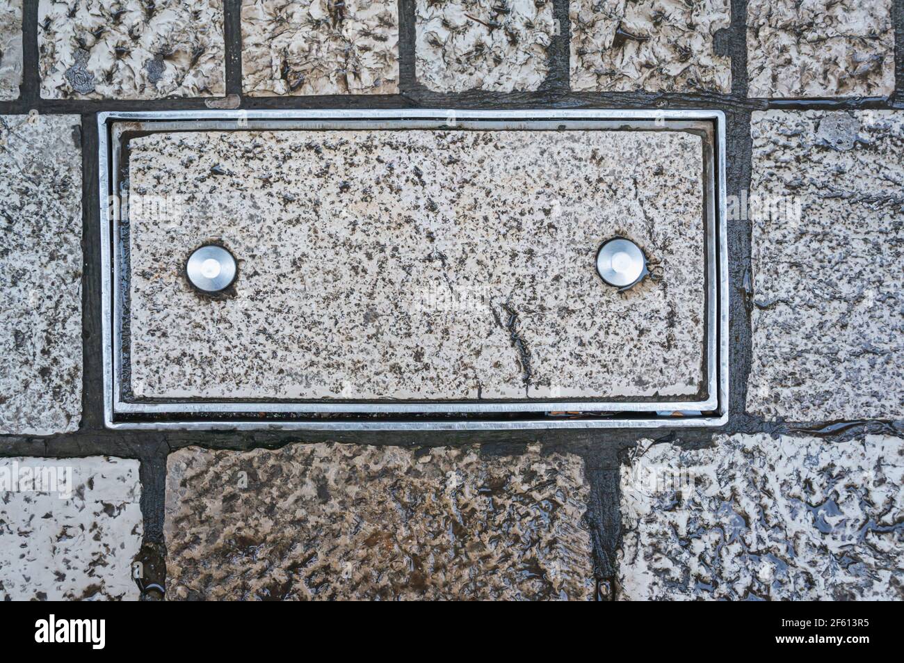 Brique dans un cadre métallique avec deux rivets. Deux goupilles métalliques sont entraînées dans le rectangle en pierre. Arrière-plan, cadre de texture pour le texte. Banque D'Images