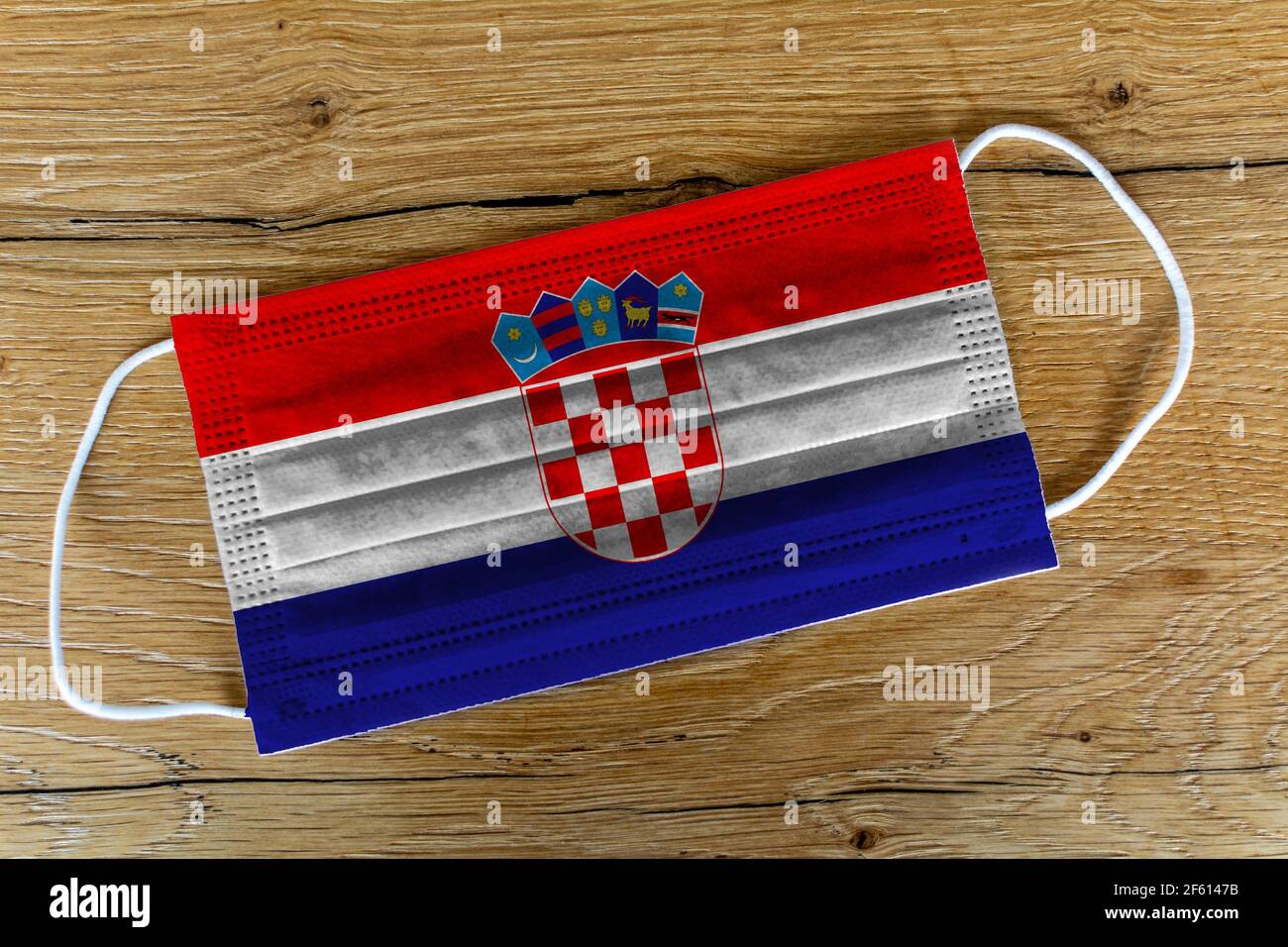 Un masque chirurgical avec le drapeau peint de la Croatie sur fond de bois. Concept de la Croatie pendant une pandémie, Covid-19, coronavirus. Banque D'Images