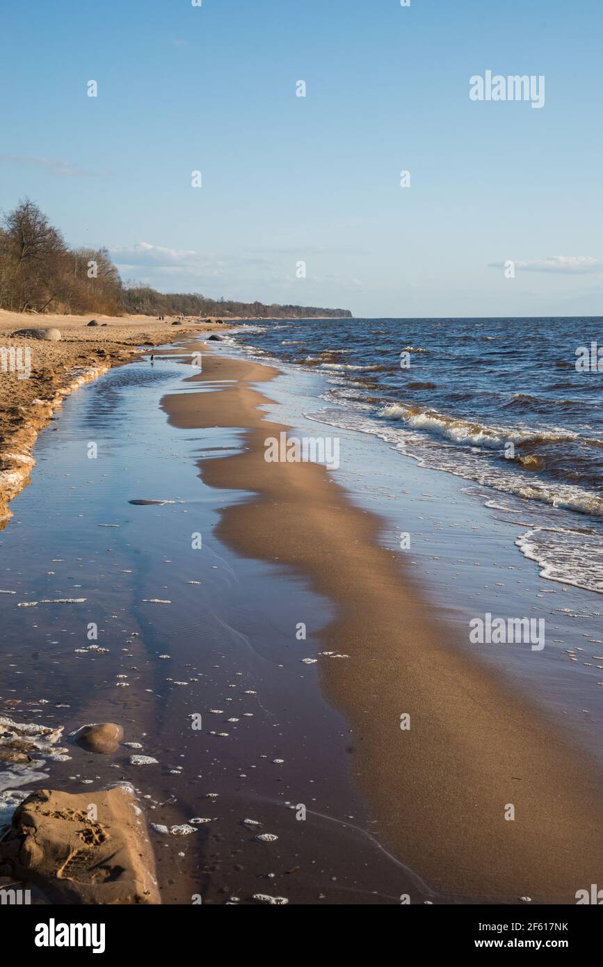 Belle plage sur la mer, qui est lavé par les vagues de l'eau de mer formant le sable humide, qui reflète le magnifique ciel bleu de printemps Banque D'Images