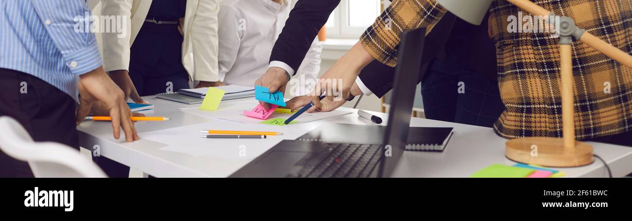 Gros plan de l'équipe de création d'entreprise au cours d'un remue-méninges pour écrire des notes sur des autocollants de couleur. Banque D'Images