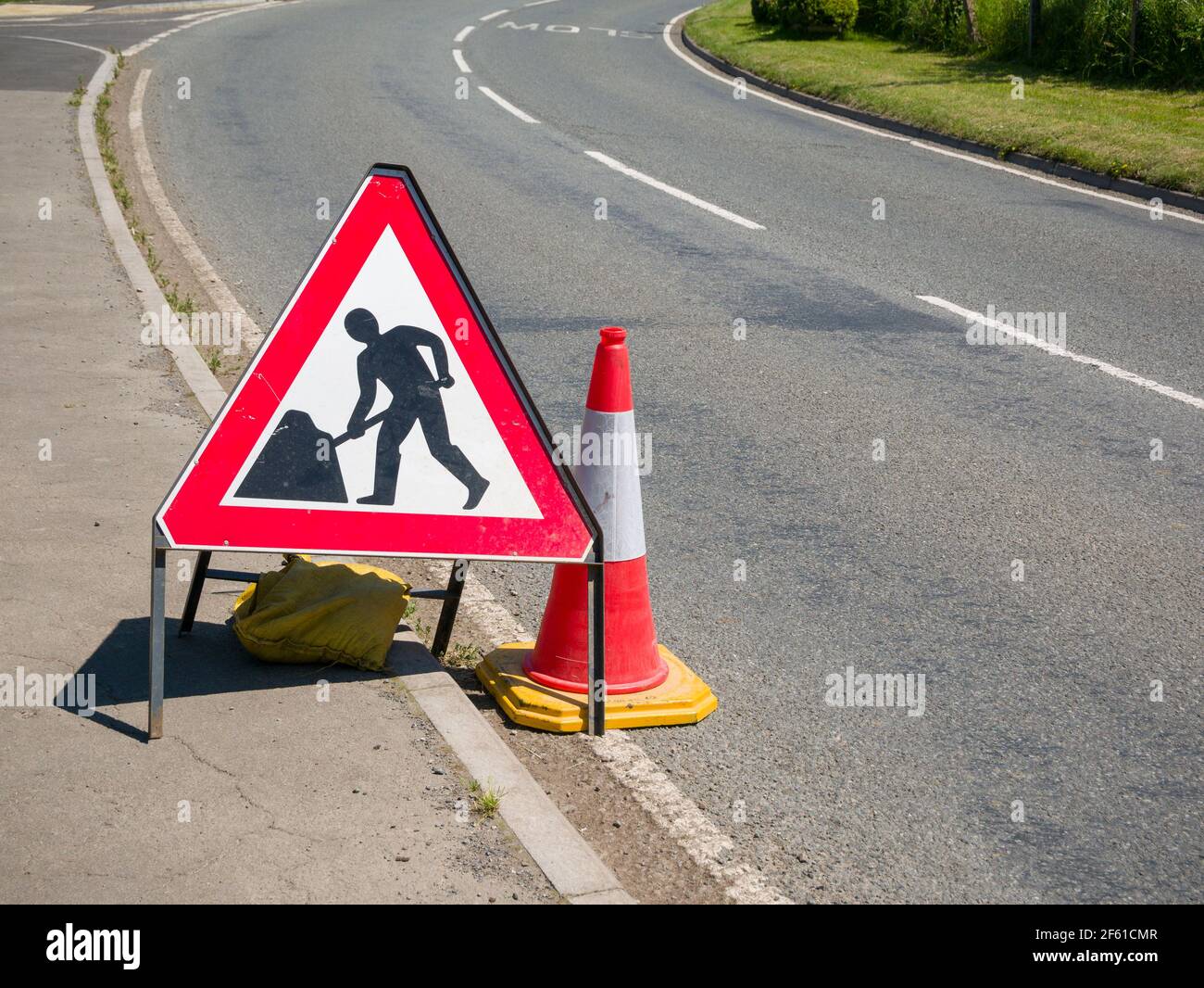 Un panneau de signalisation et un cône de circulation sur le côté d'une route au Royaume-Uni. Banque D'Images