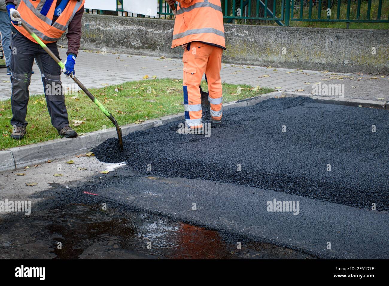 Les ouvriers de pose de revêtement ajustent la nouvelle couche d'asphalte avec les pelles vers l'intérieur reconstruction de la route Banque D'Images