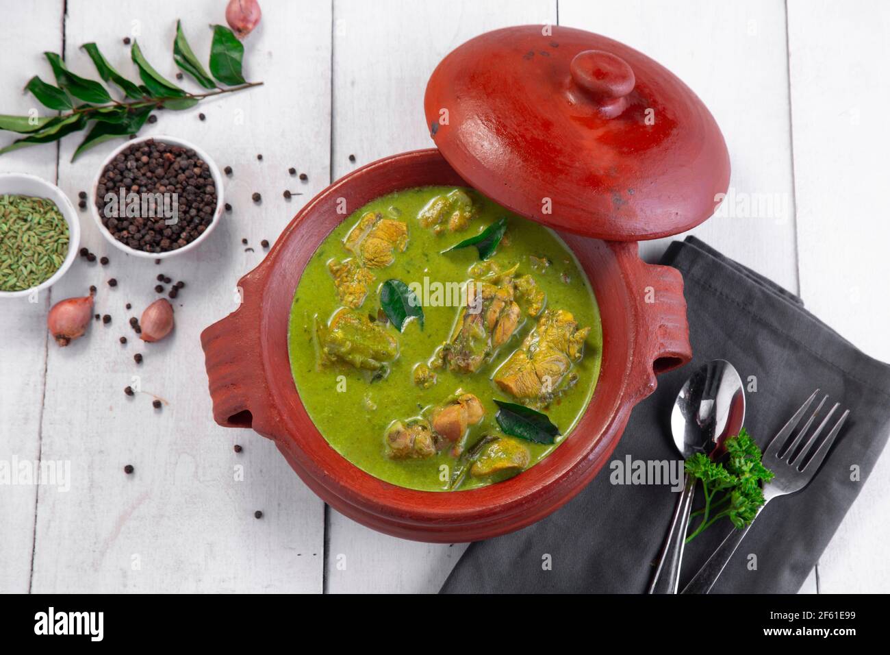 Curry de poulet vert avec ingrédients crus qui est disposé dans un matériel de terre avec fond blanc. Banque D'Images