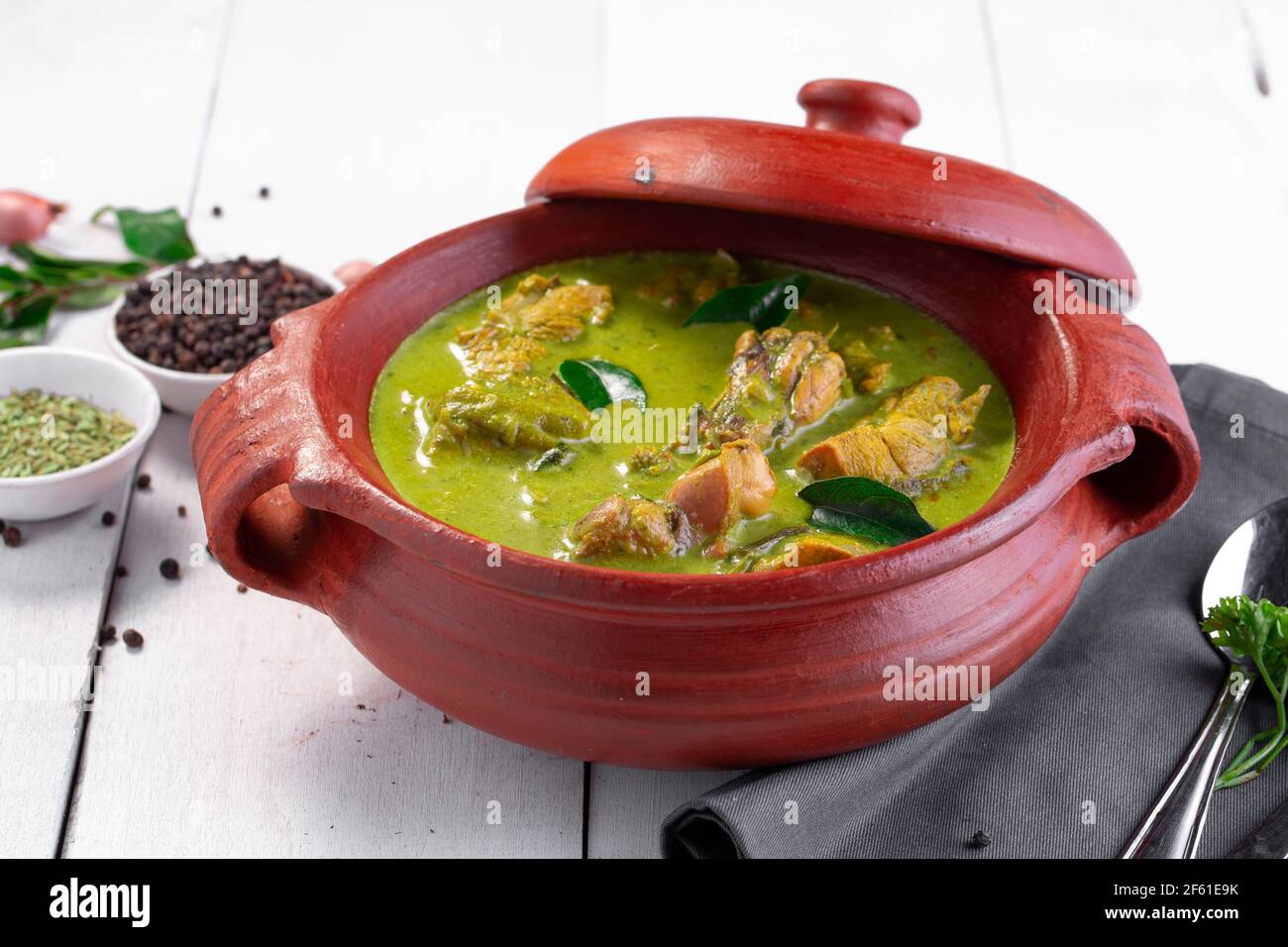 Curry de poulet vert avec ingrédients crus qui est disposé dans un matériel de terre avec fond blanc. Banque D'Images