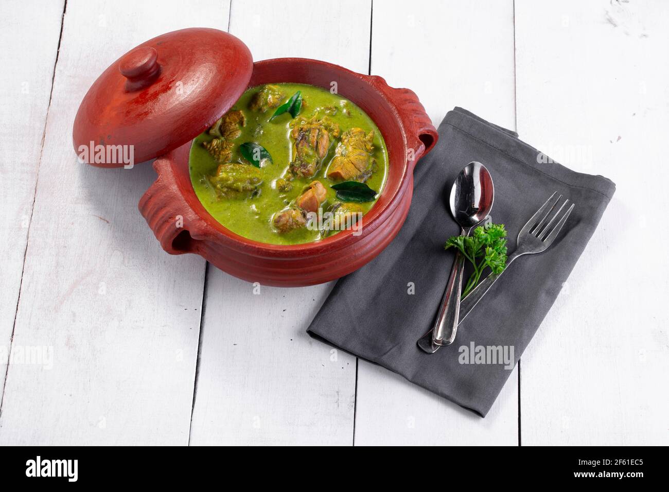 Curry de poulet vert avec ingrédients crus qui est disposé dans un matériel de terre avec fond blanc. Banque D'Images