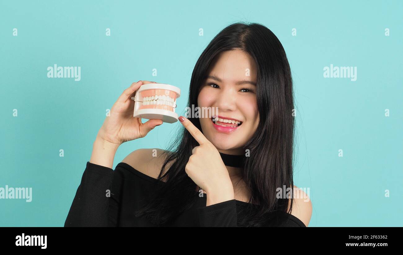 Femme tenant un modèle de dents dentaires ou un modèle orthodontique. Cheveux noirs adolescents asiatiques montrant un bloc de dents pour l'éducation. Jolie fille avec une prothèse en plastique Banque D'Images