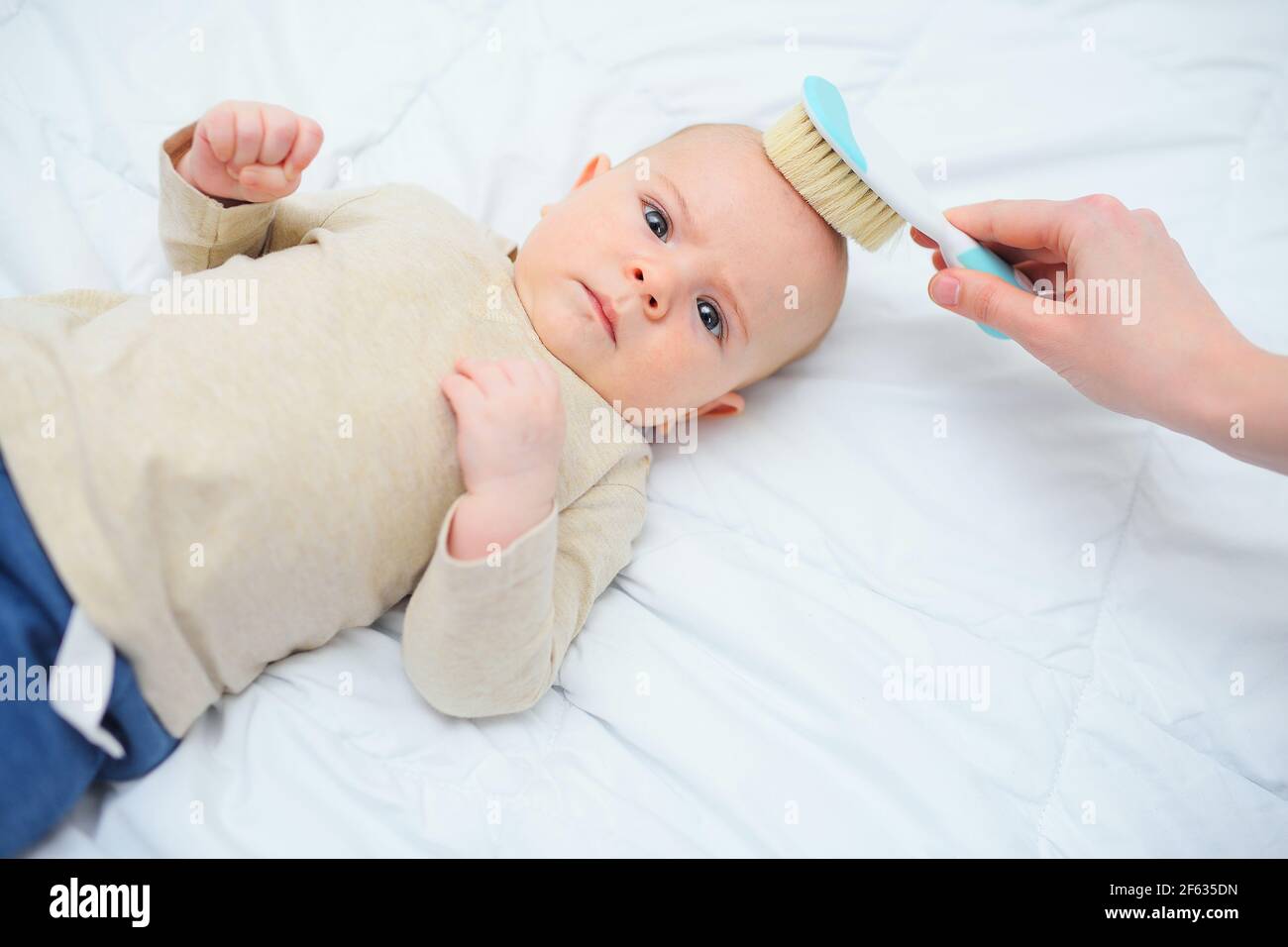 Maman Peigne Le Bebe Avec Une Brosse Speciale Sur Un Fond Blanc Photo Stock Alamy