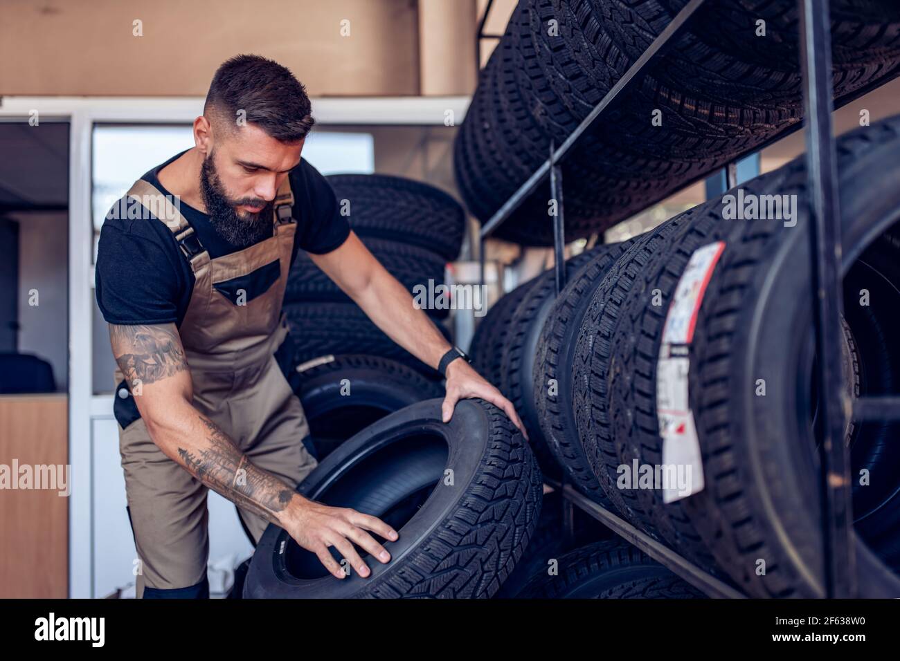 sourit pendant le processus. le mécanicien tient un pneu au garage de  réparation. remplacement des pneus d'hiver et d'été 15200113 Photo de stock  chez Vecteezy